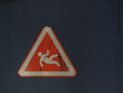 a modified "do not lean" warning sign which now looks like it reads "warning: do not abseil from this door"